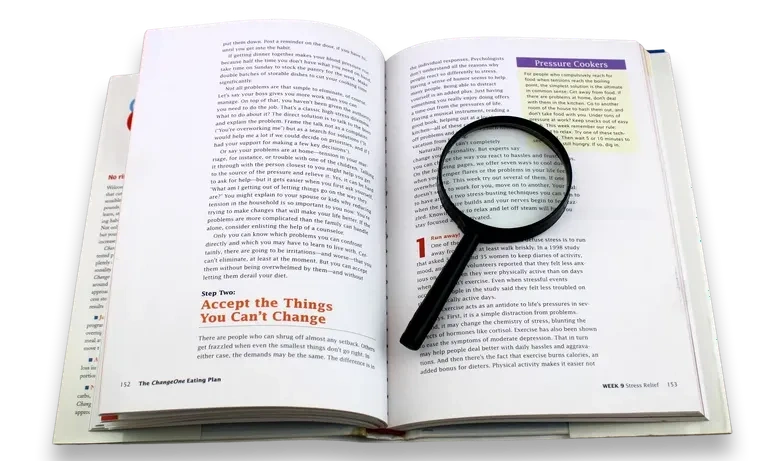 Open book with a magnifying glass over edited text